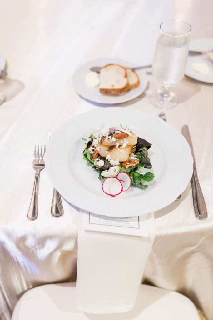 A salad with sliced pears, pecans, and crumbled cheese on a white plate, served at a kosher wedding reception in Atlanta.