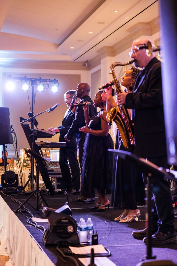 A keyboardist, two vocalists, and a saxophonist perform on stage during a kosher wedding reception in Atlanta.