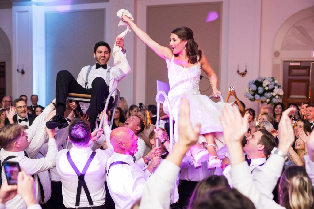 Wedding guests lift a bride and groom into the air on chairs during a kosher wedding reception in Atlanta.