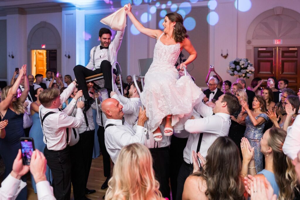 Wedding guests lift the bride and groom in chairs on the dance floor at an Atlanta kosher wedding reception.