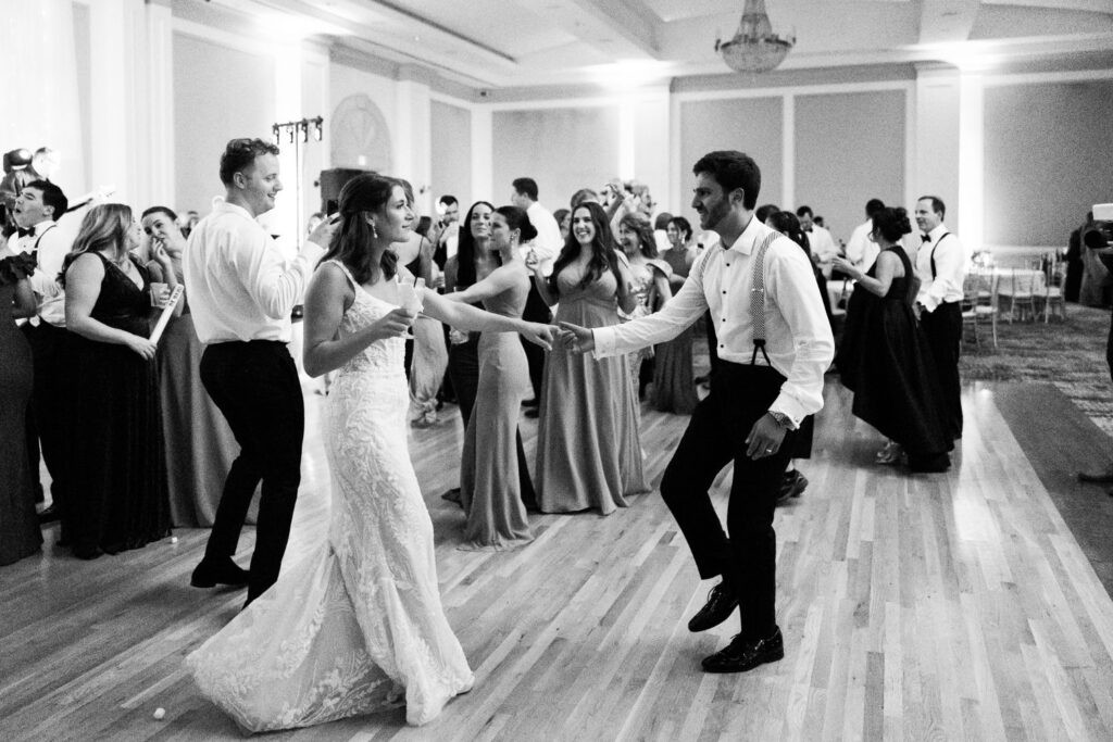 A bride and groom dancing together in the center of a crowded Atlanta kosher wedding reception ballroom.