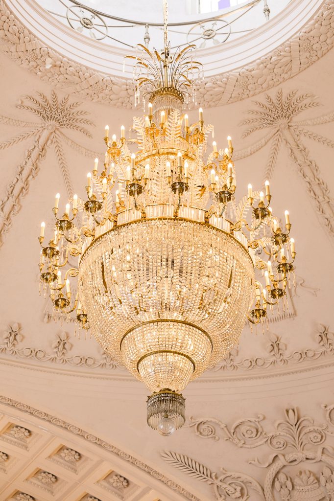 A large tiered crystal chandelier hanging from a white, ornate domed ceiling at a kosher wedding reception in Atlanta.