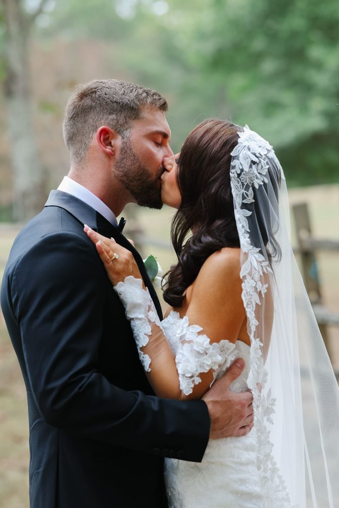 A bride and groom kissing outdoors.