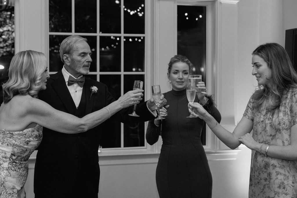 Four people toast with glasses of champagne at an indoor evening event.