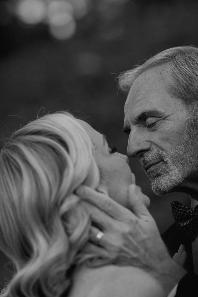 A couple in formal attire embracing face-to-face in a black and white close-up.